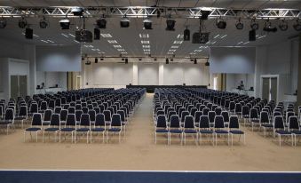 an empty conference room with rows of blue chairs and a large screen at the front at Marina Park