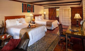 a hotel room with two beds , a dining table , and a wine glass on the table at Tubac Golf Resort & Spa