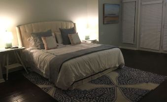 a well - lit bedroom with a large bed , multiple pillows , and a rug on the floor at The Waterford
