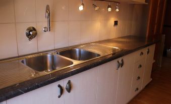 a modern kitchen with white cabinets , stainless steel sink , and countertops , under bright lights and under - cabinet lights at Copper House