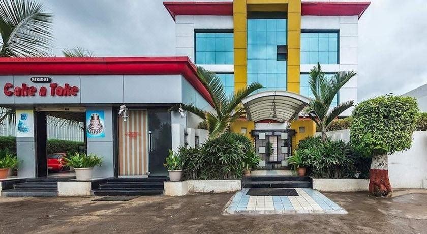 a modern building with a red and yellow facade , surrounded by lush greenery and palm trees at Hotel Paradise