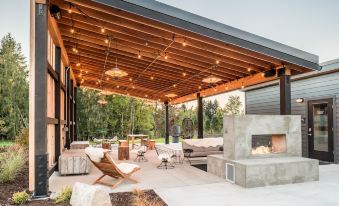 a modern outdoor living space with a patio , lounge area , and fire pit under a wooden roof at Lodges on Vashon