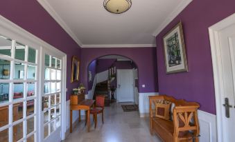 a purple hallway with a wooden chair , a table , and a chandelier hanging from the ceiling at Entre Terre et Mer