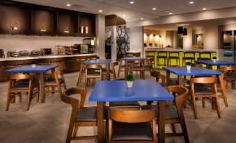 a modern restaurant with wooden tables and chairs , blue tablecloths , and a bar in the background at GLo Best Western Kanata Ottawa West
