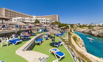 a resort with a large pool surrounded by lounge chairs and umbrellas , as well as a view of the ocean at Globales Almirante Farragut