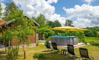 a large outdoor hot tub surrounded by green grass and trees , with several lounge chairs placed around it at Tina