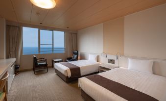 a hotel room with two beds , one on the left side and one on the right side of the room at Kamenoi Hotel Atami Annex