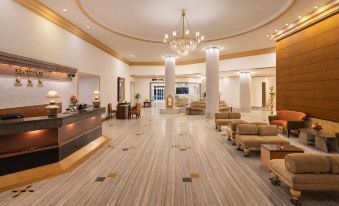 a large hotel lobby with wooden floors , a marble reception desk , and a chandelier hanging from the ceiling at Sangam Hotel, Thanjavur