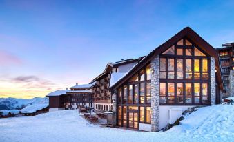 a large , snow - covered building with multiple floors and a clear view of the surrounding landscape at Hotel l'Eden des Cimes - Vacances Bleues - Belle Plagne 2100