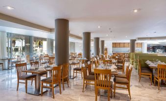 a large , empty dining room with wooden tables and chairs arranged for a group of people at Minos Boutique Hotel