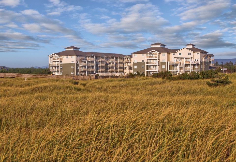 a large apartment building surrounded by tall grass , with a cloudy sky in the background at WorldMark Long Beach