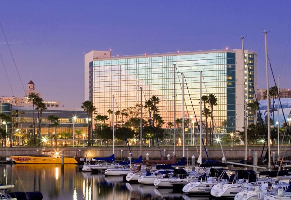 a marina with several boats docked , including sailboats and motorboats , and a large building in the background at Hyatt Regency Long Beach