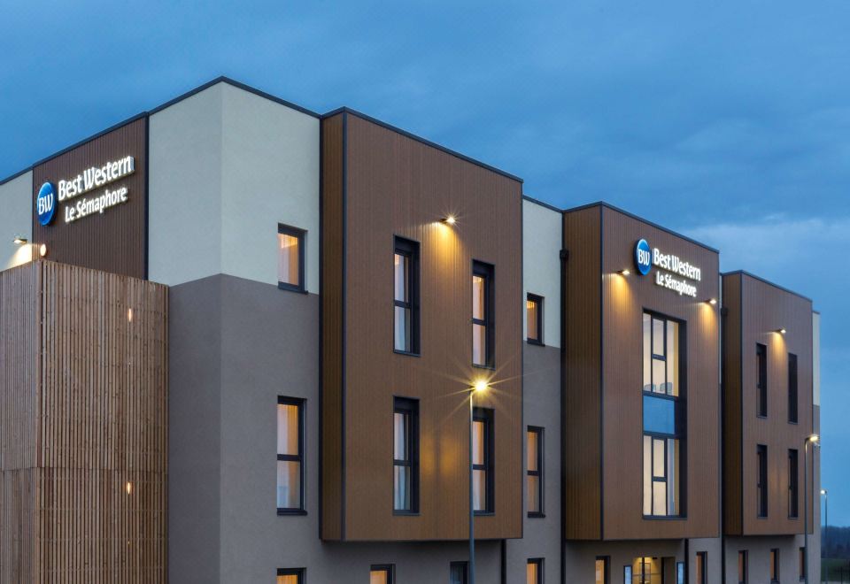 "a modern building with a sign that says "" hotel bon - ami "" is illuminated against a blue sky" at Best Western Hotel le Semaphore