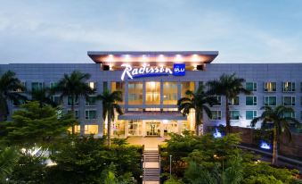 "a large building with the word "" radisson "" prominently displayed on it , surrounded by palm trees and other greenery" at Radisson Blu Anchorage Hotel