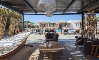 a patio area with various furniture , including chairs , tables , and a pool , under a covered structure at Parosland Hotel