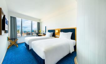 The modern-style bedroom features double beds and large windows that overlook the pool area at Holiday Inn Express Macau City Centre