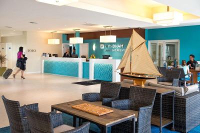 a hotel lobby with a reception desk , several chairs , and a sailboat model on display at Wyndham Reef Resort Grand Cayman