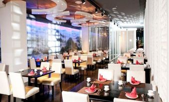 a large dining room with white tables and chairs , a view of the city through a window at The Riverside Hotel