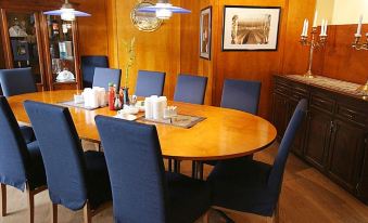 a wooden dining table with chairs surrounding it in a room with blue walls and wooden paneling at Hotel Savoy