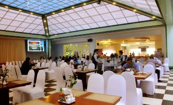 a large dining room with white chairs and tables , and a crowd of people seated at the tables at Tre Xanh Hotel