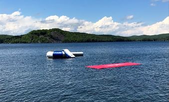 a body of water with a boat floating on it , surrounded by trees and mountains at Lake Bomoseen Lodge