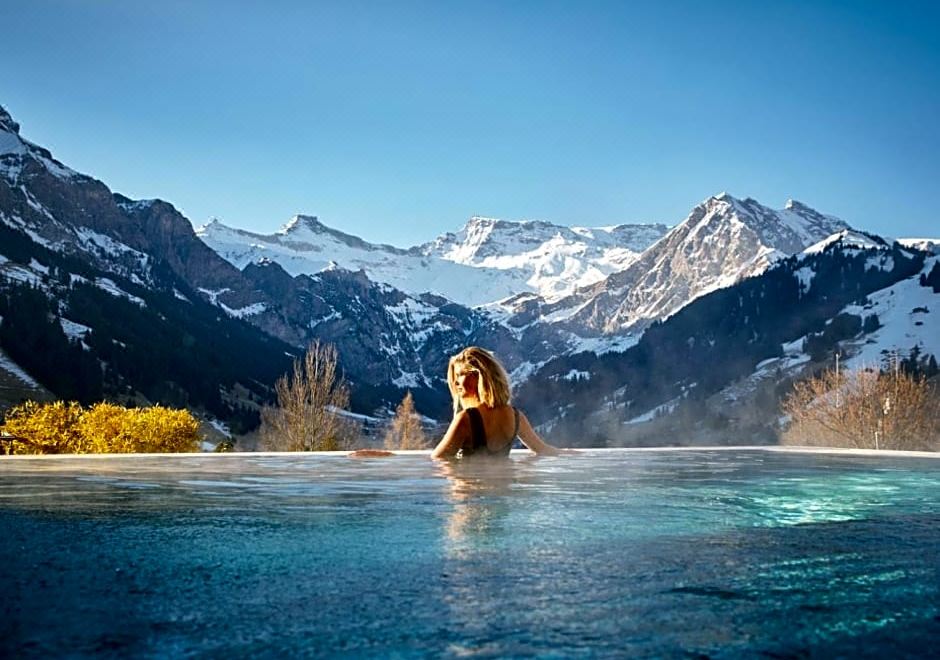 a woman is relaxing in a hot tub surrounded by snow - covered mountains , enjoying the view at The Cambrian