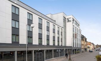 a modern building with white and gray exterior panels , balconies , and people walking on the street at Best Western Plus Hus 57