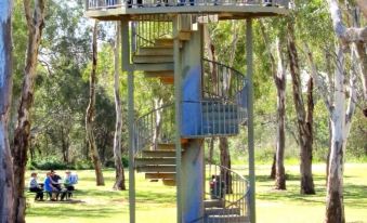 a group of people standing on a metal staircase in a park , surrounded by trees and grass at Two Rivers Motel