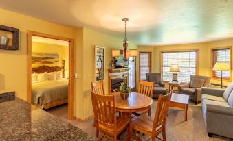 a living room with a dining table and chairs , a fireplace , and a bedroom in the background at Newport Resort