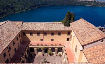 a courtyard with a view of a lake and mountains , surrounded by buildings with orange roofs at Villa Palazzola