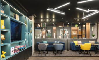 a modern living room with blue couches , wooden furniture , and shelves filled with various items at Holiday Inn Leeds - Wakefield M1, Jct.40