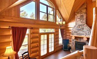 a wooden cabin interior with large windows , a fireplace , and a rocking chair , offering a view of the outdoors at Fiddler Lake Resort