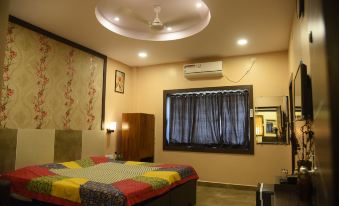 a cozy bedroom with a bed , curtains , and an air conditioner , decorated with a quilt on the bed at HOTEL ASHOKA