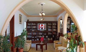 a cozy living room with multiple couches , chairs , and bookshelves , as well as a tv mounted on the wall at Rose Gardens