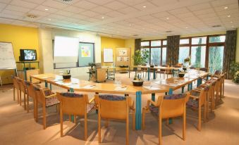 a large conference room with a round table surrounded by chairs and a whiteboard on the wall at Hotel Sonnenblick
