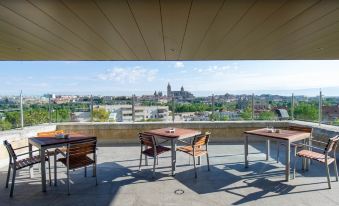 a rooftop terrace with a view of the city , where several chairs and tables are arranged for dining at Parador de Salamanca