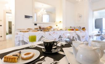 a dining table with a cup of coffee , a plate of cookies , and a glass of juice at Hotel San Giovanni