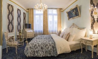 a large bed with a floral blanket is in the middle of a room with a chandelier and framed pictures at Hotel Alexandra