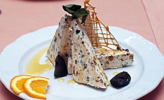 a dessert with a slice of cake and a drizzle of sauce is presented on a plate at Festa Winter Palace Hotel