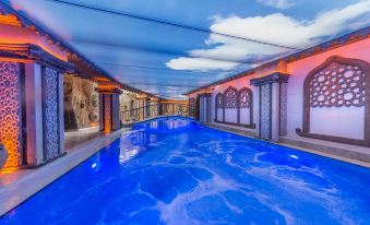 a large , blue swimming pool with a diving board and chairs under a covered area at Kapadokya Hill Hotel & Spa (12+)