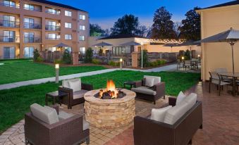 an outdoor patio with a fire pit surrounded by several chairs and a couch , creating a cozy atmosphere at Sonesta Select Raleigh Durham Airport Morrisville