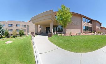 a large building with a curved entrance is surrounded by grass and trees , under a clear blue sky at Squire Resort at The Grand Canyon, BW Signature Collection