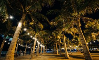 A row of people walking around under umbrellas on the beach at night at Hotel Sogo Macapagal