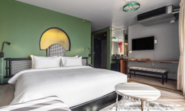 The bedroom is furnished with a white bed, a large mirror, and a table in the center of the room at MeStyle Museum Hotel