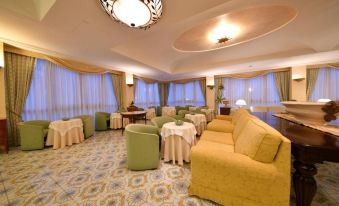 a well - lit hotel lobby with multiple couches , chairs , and tables arranged for guests to relax at Grand Hotel Terme di Augusto