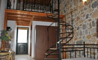 a spiral staircase with a wooden railing is in a room with a stone wall and wooden door at Villa Victoria