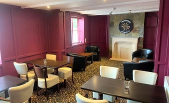 a large room with multiple tables and chairs , a fireplace , and a dartboard on the wall at The White Horse