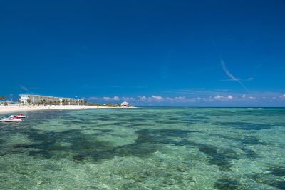 a beautiful beach with clear blue water and a white building on the other side at Wyndham Reef Resort Grand Cayman