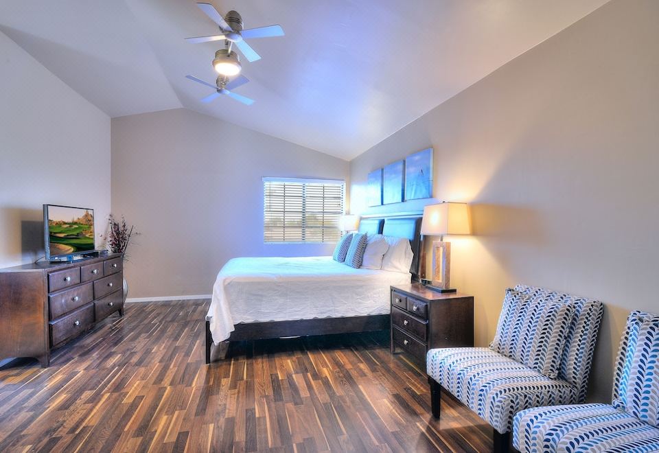 a spacious bedroom with hardwood floors , a large bed , and a ceiling fan on the wall at Arrowhead