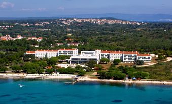 aerial view of a large resort hotel surrounded by water and trees , with a beach in the background at Park Plaza Belvedere Medulin